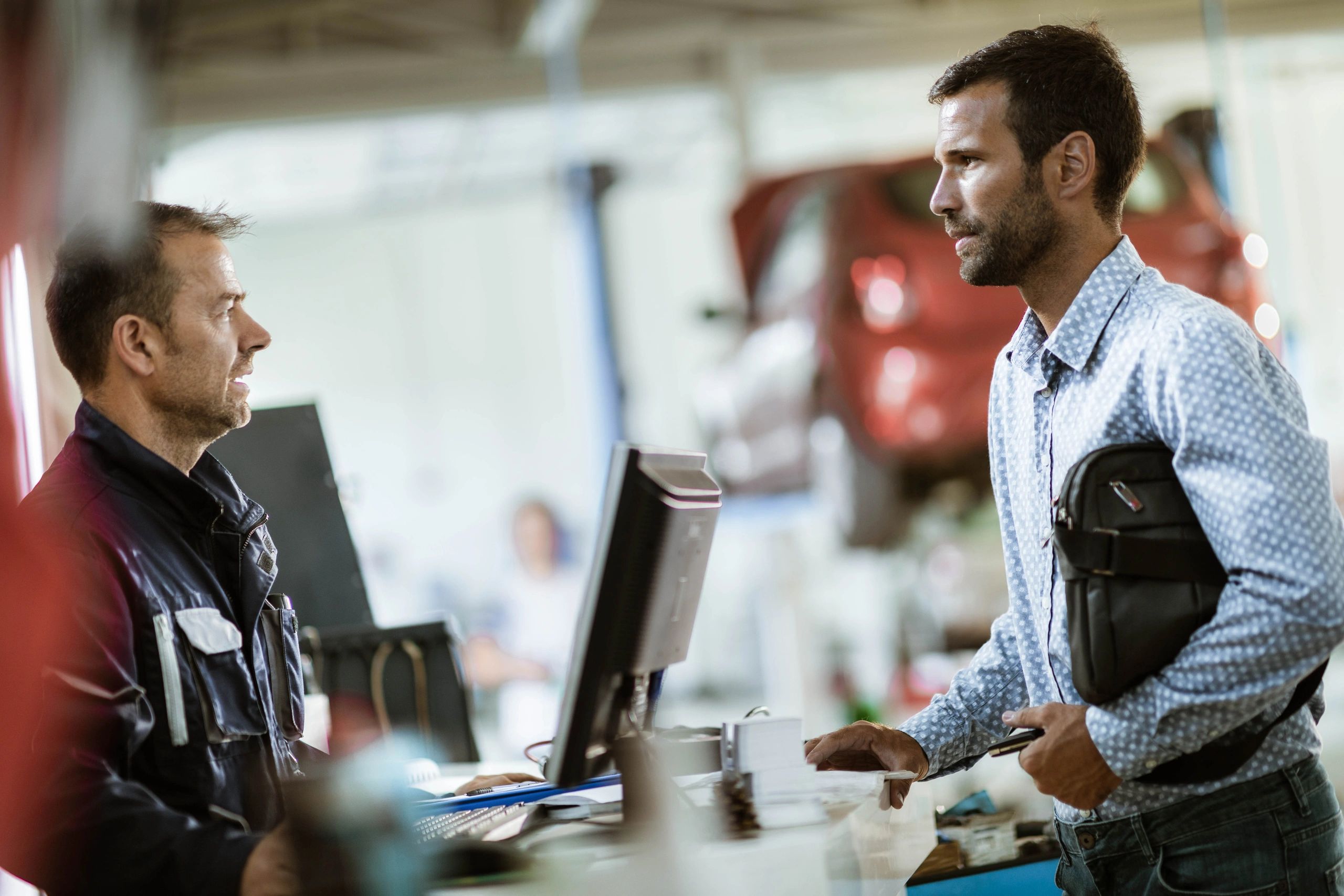 Customer talking with an auto mechanic in a repair shop